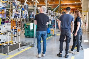 Lors des portes ouvertes de l'usine, un groupe de personnes regarde avec attention les photographies exposées à la fin du parcours (issues du reportage métier réalisé au sein de l'entreprise)