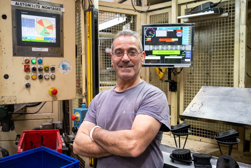 Reportage en industrie. Portrait posé d'un salarié devant sa machine, dans le secteur industriel.