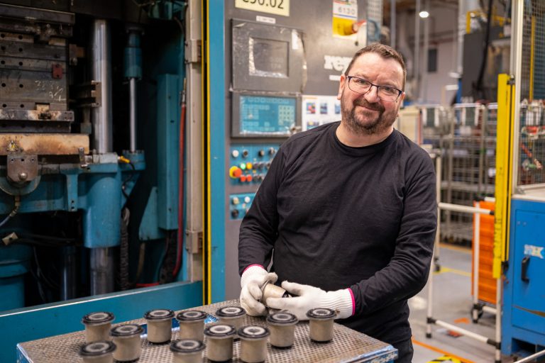 Reportage en industrie. Portrait sur le vif d'un salarié d'une entreprise industrielle, salarié regardant l'objectif avec une pièce entre les mains.