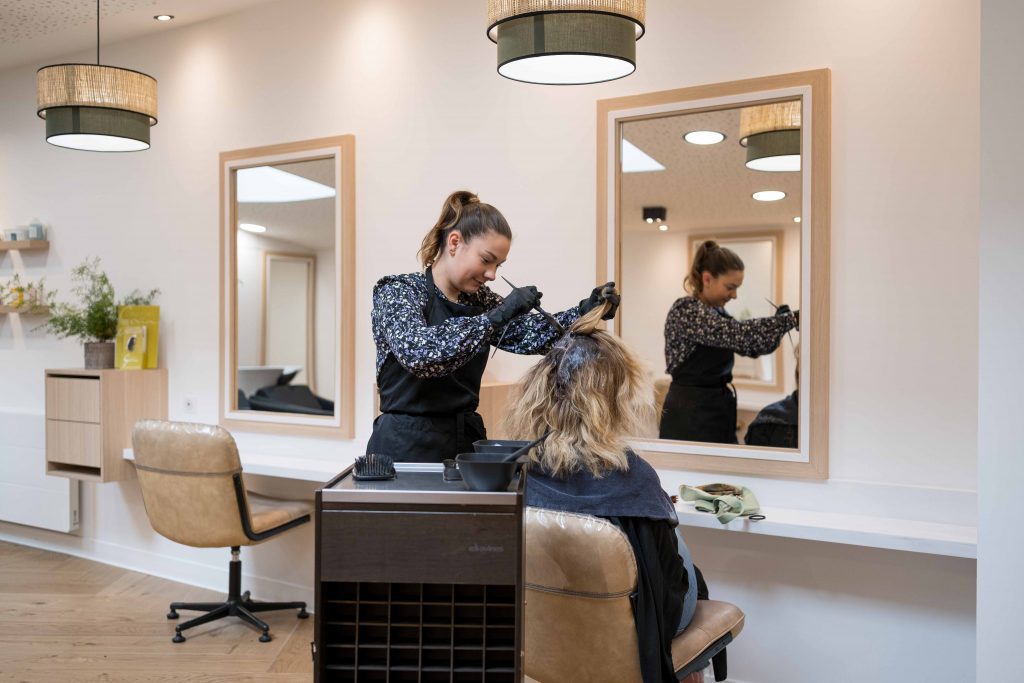 Coiffeuse réalisant une couleur à une cliente