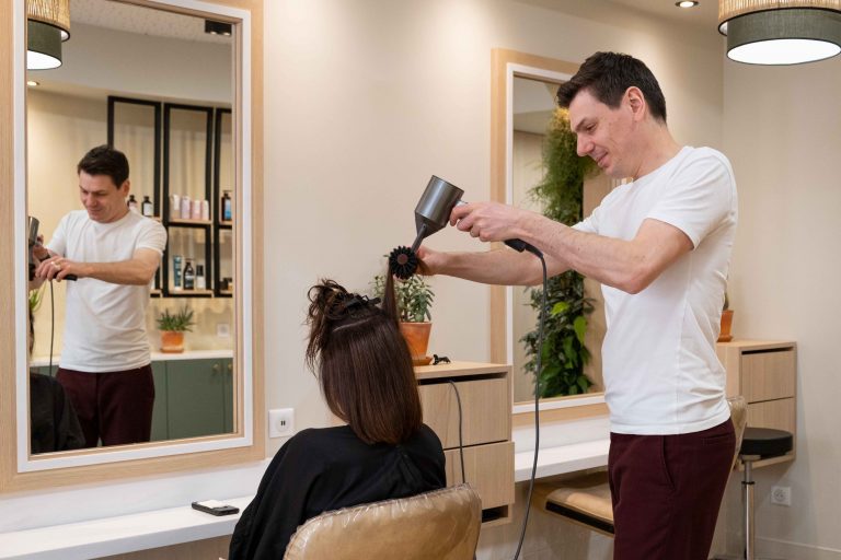 Coiffeur séchant les cheveux de sa cliente dans la bonne humeur