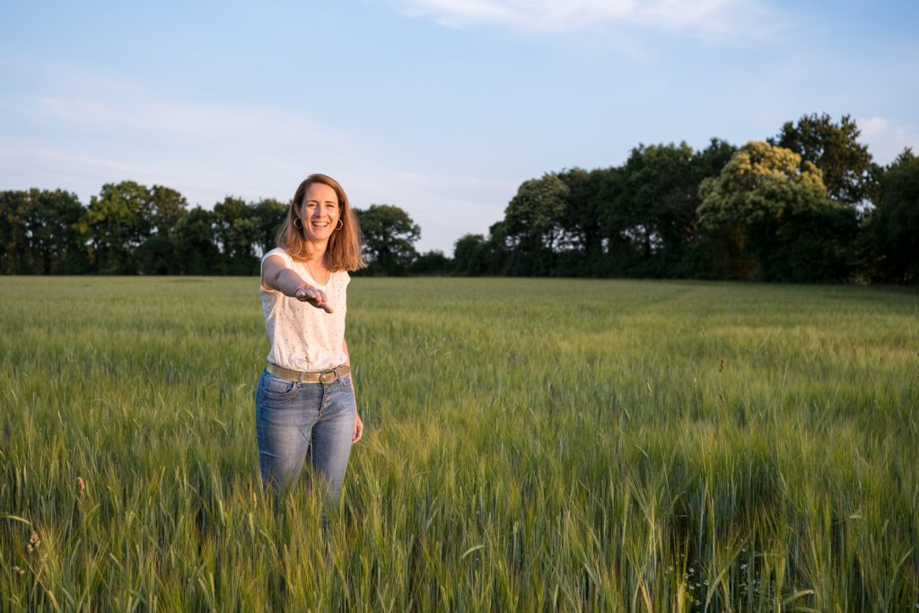 Portrait professionnel entrepreneure. Portrait de Marie Tournier, énergéticienne, dans un champ, au coucher du soleil.