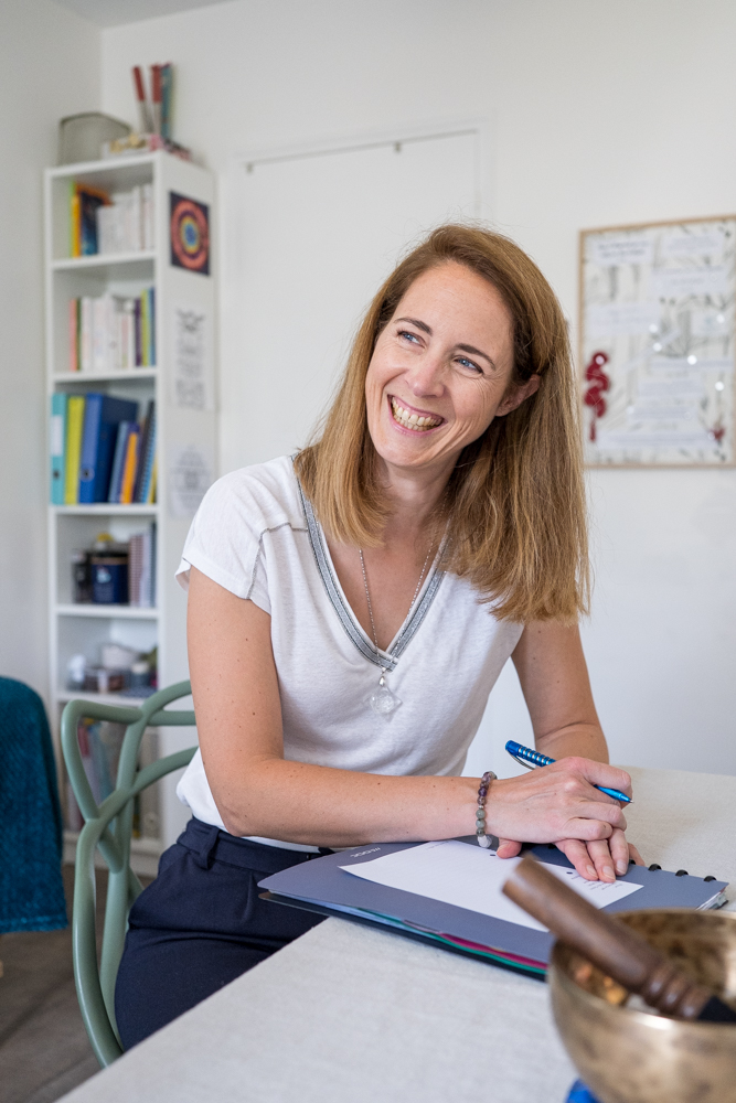 Reportage métier auprès de Marie Tournier, énergéticienne, dans son cabinet, souriante en consultation