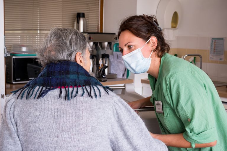 Agente d'hôtellerie en EHPAD échangeant avec une résidente dans la salle de restauration